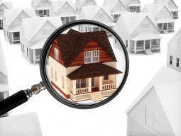 Photo illustration of a house beneath a magnifying glass standing out from the others in the neighborhood